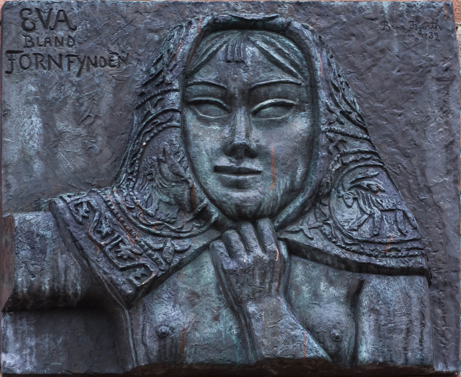 Bronsrelief med motiv av en kvinna i huckle.