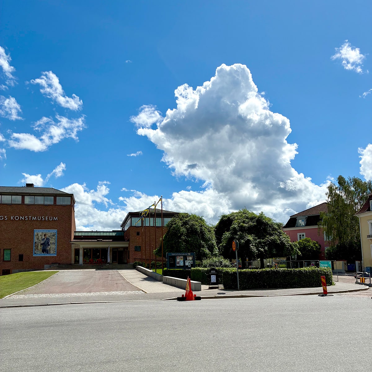 Puff-parkering på baksidan avstängd Konstmuseets entré, tegelbyggnad med stor gräsmatta och grusplan framför, hissade vimpllar.